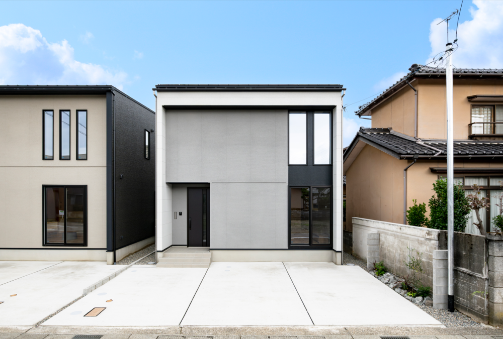 シンプルなグレーの外観に、軒と袖壁がつくる陰影が建物に奥行きをもたらし、街並みに自然と溶け込みながらも印象に残るデザインの住まい。