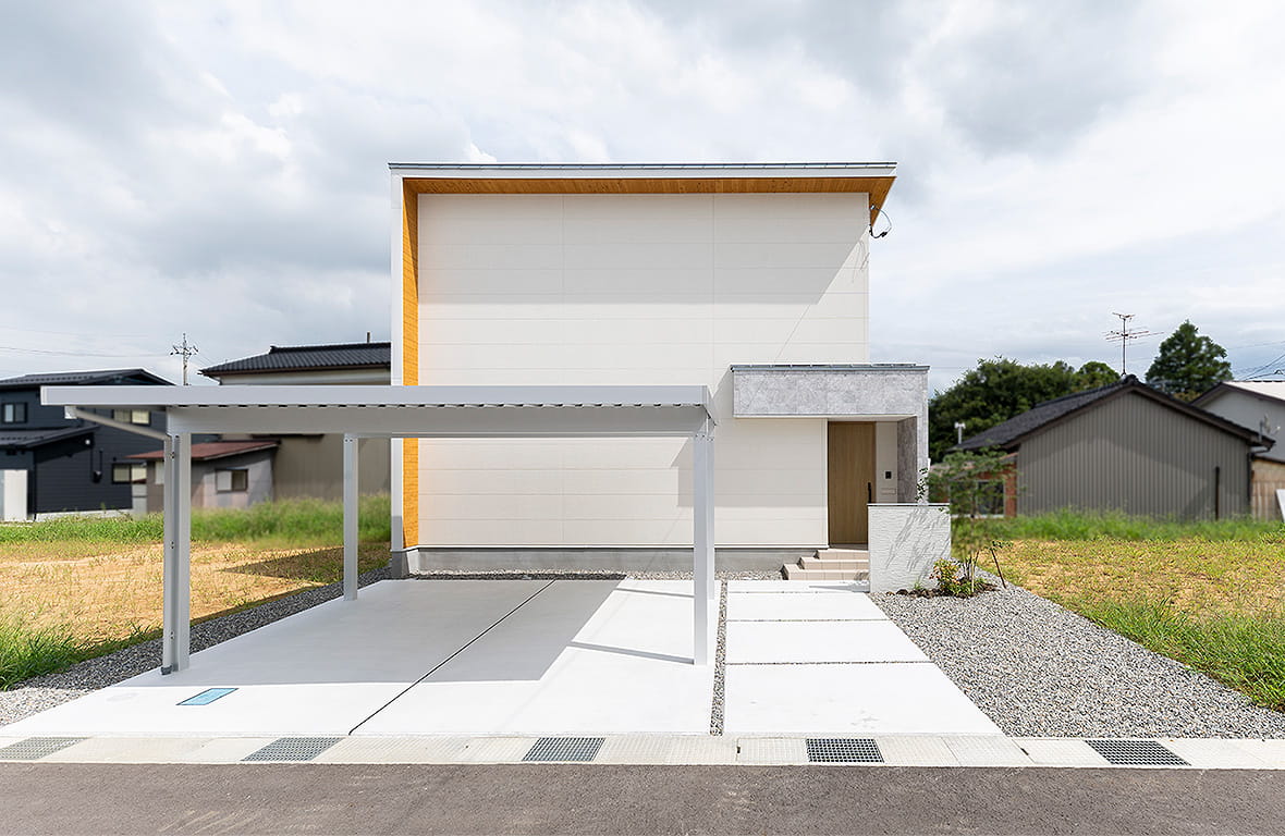 白を基調としたスタイリッシュな外観。すっきりとしたデザインとカーポートを備えた、モダンで洗練された住宅のファサード。